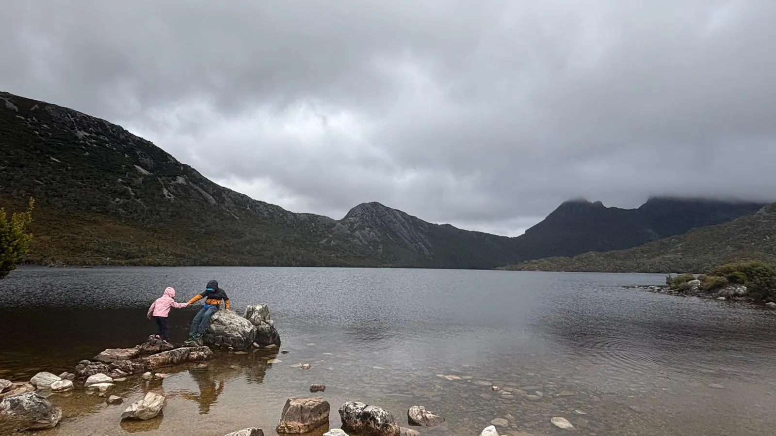 Adult giving a child a hand while crossing the Dove Lake circuit at Cradle Mountain, Tasmania