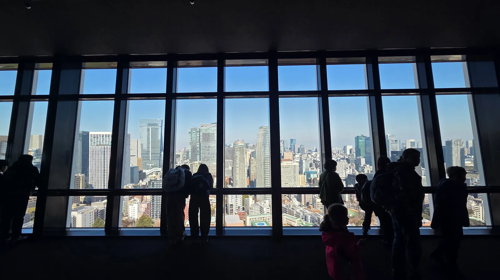 Family silhouettes looking out over the Tokyo skyline from Tokyo Tower's observation deck